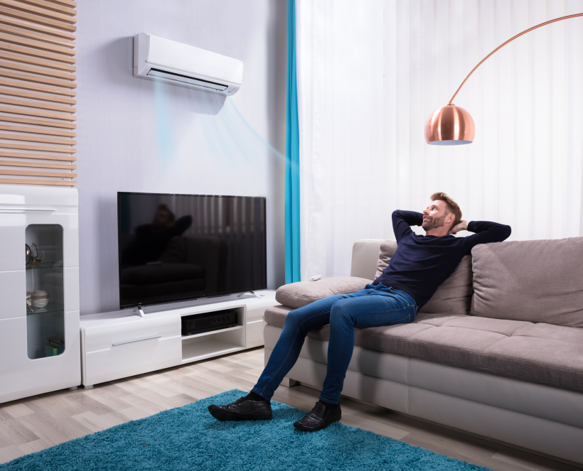 Modernes Wohnzimmer mit Couch, TV und Klimaanlage.